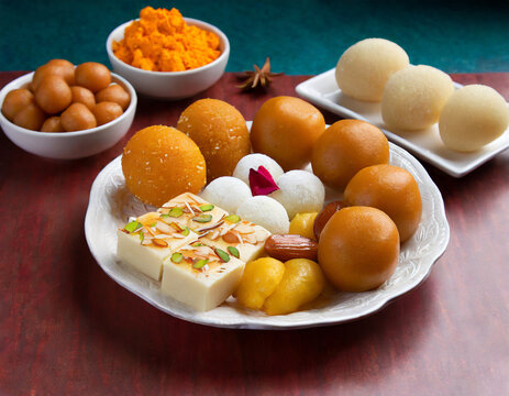 Indian sweets in a plate includes Gulab Jamun, Rasgulla, kaju katli, morichoor / Bundi Laddu, Gujiya or Karanji for diwali celebration