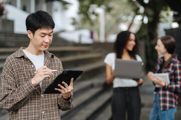 Fototapeta premium college student reading a book study on laptop prepare for the exam Or work on a group project while sitting on the steps of the university.