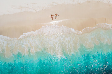Man and woman lying down on a tropical beach, Drone view from above at a tropical beach in the Seychelles Cocos Island, view from above at a tropical beach, a couple on vacation tropical Island - obrazy, fototapety, plakaty