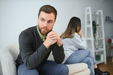 Man and woman feeling stressed and angry at each other, frustrated couple sitting back to back,...