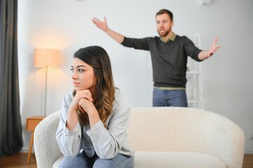 Emotional man gesturing and shouting at his wife, young couple having quarrel at home. Domestic abuse concept