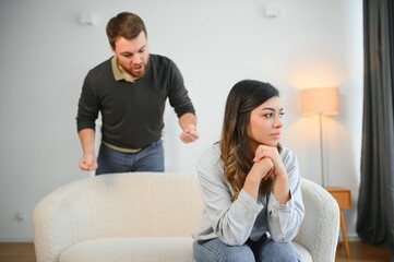 Boyfriend and girlfriend are arguing at home. Angry man is yelling at his sad girlfriend