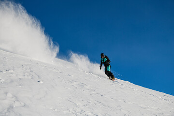 One-armed male snowboarder on his snowboard overcomes a route on a smooth snowy slope