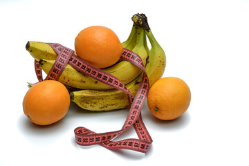Banany i pomarańcze, owoce w diecie, owinięte centymetrem na białym tle - obrazy, fototapety, plakaty