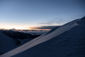 Close-up photo of a snow-covered slope against the background of other mountains