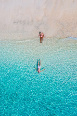 drone view of a man and woman swimming in the blue turqouse colored ocean of Koh Kradan island in Thailand. top view from above at the beach of Koh Kradan Trat Thailand © Fokke Baarssen