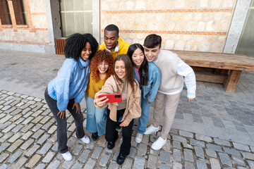 A group of six friends taking a selfie happily on a cobblestone street, radiating happiness and unity