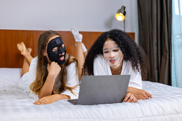 Couple of girlfriend in bathrobe with facial mask on spa night for beauty skin and treatment while...