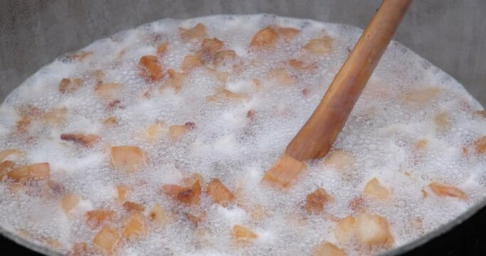 Preparation of delicious unhealthy fried pork greaves in a cauldron on the open fire. Delicious fried pork greaves in the pan traditional Romanian Christmas dish. Crispy deep fried