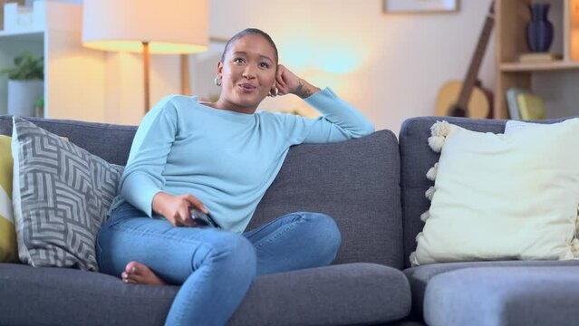 Woman laughing while watching a funny tv series on a couch at home. Happy female sitting in front of television to enjoy a weekend of hilarious entertainment. Streaming comedy movies and sitcom shows