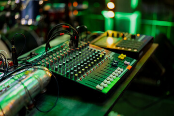 Audio mixing console close up with green colored party event background