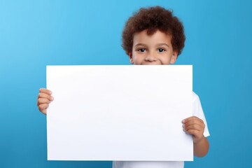 Little boy holding a blank white sheet of paper