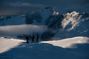 Expedition of three male skiers stand on a snowy slope in full gear