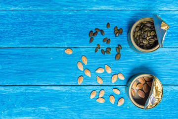 Open can with pumpkin and sunflower seeds on vintage weathered blue wooden boards. Top view.