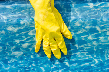 Close-up of a hand in a rubber glove while cleaning a garden pool. Preparation of the pool for the summer swimming season