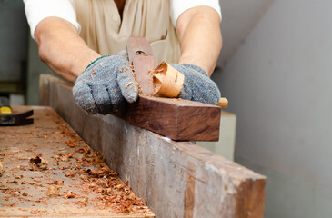 Carpenter's hands planing a plank of wood with a hand plane