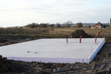 Prepared base plate on the plot. We see straight poured concrete in which water pipes are prepared.