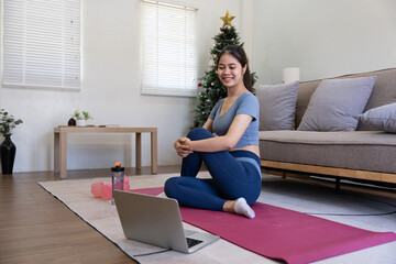 Young Asian sporty fitness woman coach do practice video online training yoga laptop in living room...