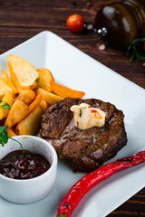 Beef fillet steak with Rustic fried potato wedges, onions, chili peppers, cherry tomatoes and sauce, dinner.