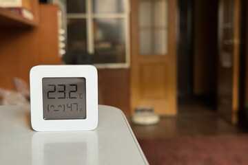Comfortable humidity and temperature in the apartment. White hygrometer on the table
