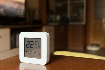 Comfortable humidity and temperature in the apartment. White hygrometer on the table - obrazy, fototapety, plakaty