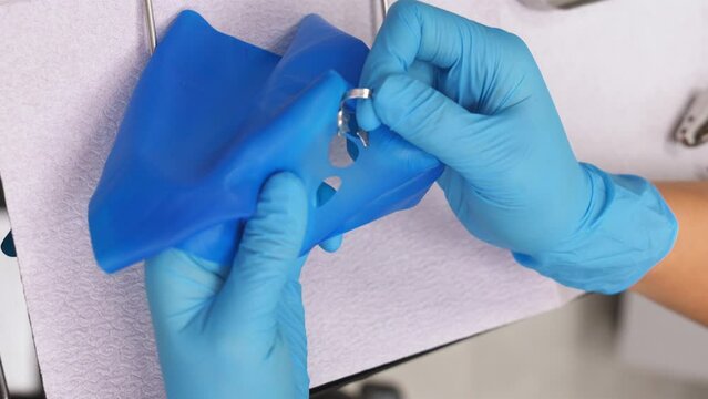 Preparing cofferdam for consumption. Dentist uses dental dam with latex scarves and shows hole with special tool. Modern dentistry. Vertical video.