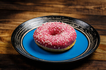 Sweet pink donut on wooden table, pink dessert