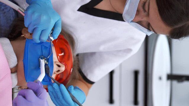 Restoration chewing surface with photopolymer filling material. Dentist working with dental polymerization UV lamp in oral cavity. Modern dentistry. Vertical video