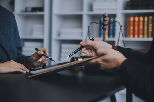 Business and lawyers discussing contract papers with brass scale on desk in office. Law, legal services, advice, justice and law concept picture with film grain effect