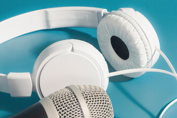 White headphones and scenic microphone on a blue background. close-up