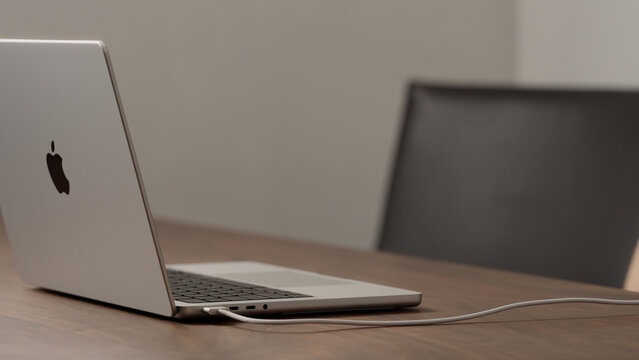 Saint-Petersburg, Russia - Circa December, 2022: new Macbook on walnut wood table with charging cable