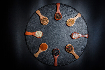 Obraz na płótnie Canvas All types of spices on a black background, different spices in spoons on a black background, beautiful spices in spoons