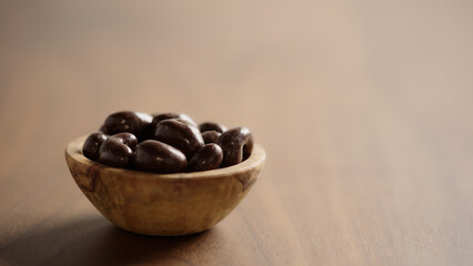 Chocolate covered cashew in a wood bowl closeup