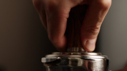 closeup of tamping fresh ground coffee in portafilter