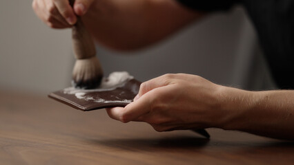 man cleaning leather wallet on wood table