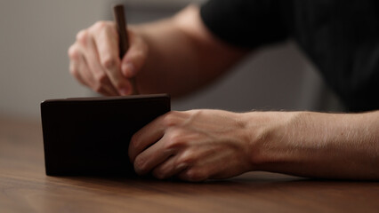 man cleaning leather wallet on wood table