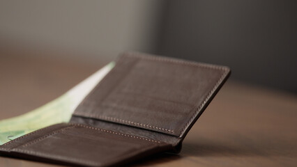 closeup man counting money in brown leather wallet
