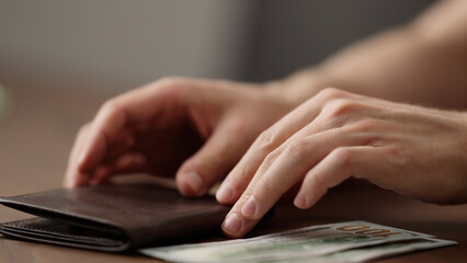 closeup man counting money in brown leather wallet