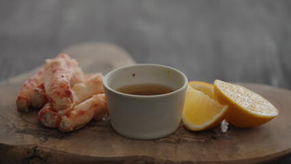 Slow motion gimbal shot of crab leg meat on a olive board with sweet lemon and dip sauce