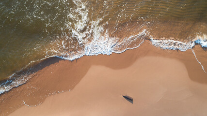 Ocean waves on the beach as a background. Beautiful natural summer vacation holidays background. Aerial top down view of beach and sea with blue water waves.