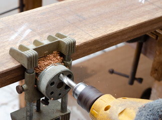 Carpenter working with drill leaning over table at carpentry workshop