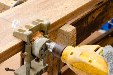 Carpenter working with drill leaning over table at carpentry workshop