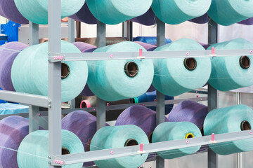 Large spools of thread on a loom in a weaving factory