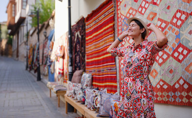 Fototapeta na wymiar female summer travel to Antalya, Turkey. young asian woman in red dress walk through old town Kalechi , female tourist traveler discover interesting places and popular tourist traditional carpet