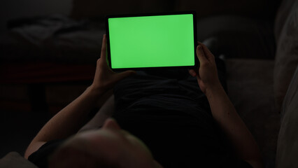 Man at home lying on a couch with tablet pc with green screen