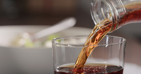 pour organic cola drink into tumbler glass on linen cloth with copy space