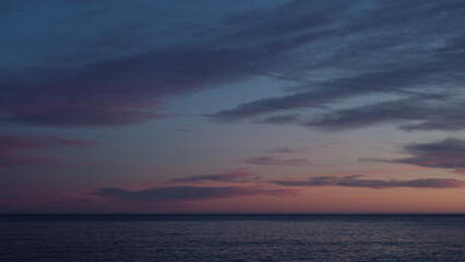 Beautiful sunset with purple clouds and flying birds over the sea