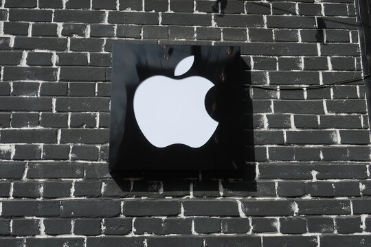 Apple logo, sign, symbol on a black brick wall at Apple store. KYIV, UKRAINE - APRIL 5, 2021