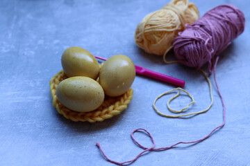 Easter eggs and cotton yarn threads on textured background with copy space. Easter decoration. 