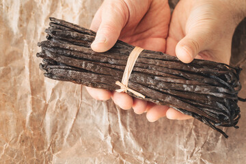 the world's best vanilla from Madagascar, premium quality, aromatic addition to cakes and desserts, a bunch of whole vanilla beans in paper, tasty and healthy organic additions in the kitchen - obrazy, fototapety, plakaty